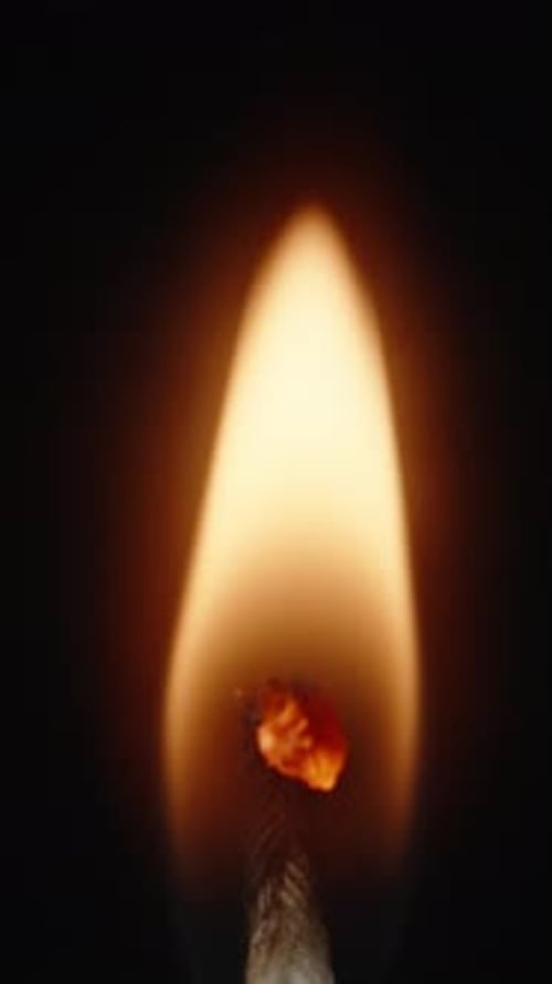 Burning candle wick on a black background. Close-up. Vertical video.