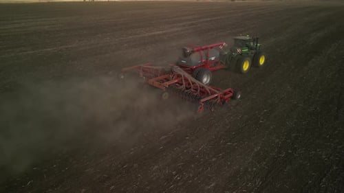 Green tractor seeding wheat on the field