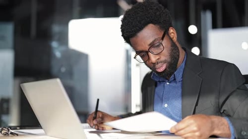 Businessman Working at Office Desk with Laptop and Documents