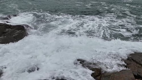 Ocean Waves Crashing on Black Stones Shoreline Corner