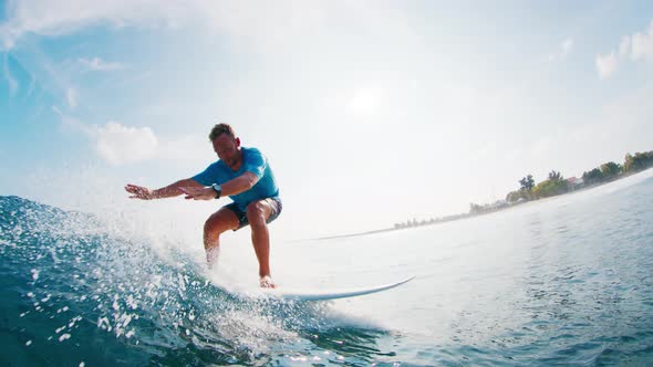 Male surfer rides the wave, passes by and watches into the camera ...