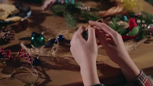 Hands Preparing Christmas Decorations on Wooden Table