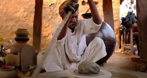Potter lance le tour du potier et façonne un pot en céramique dans un atelier de poterie