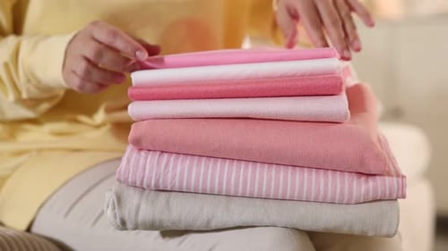 Woman with stack of clothes on sofa indoors, closeup
