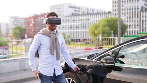 Man Charging Electric Car with VR Headset