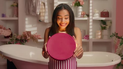 Young Woman Opening a Glowing Gift Box with a Surprised Expression