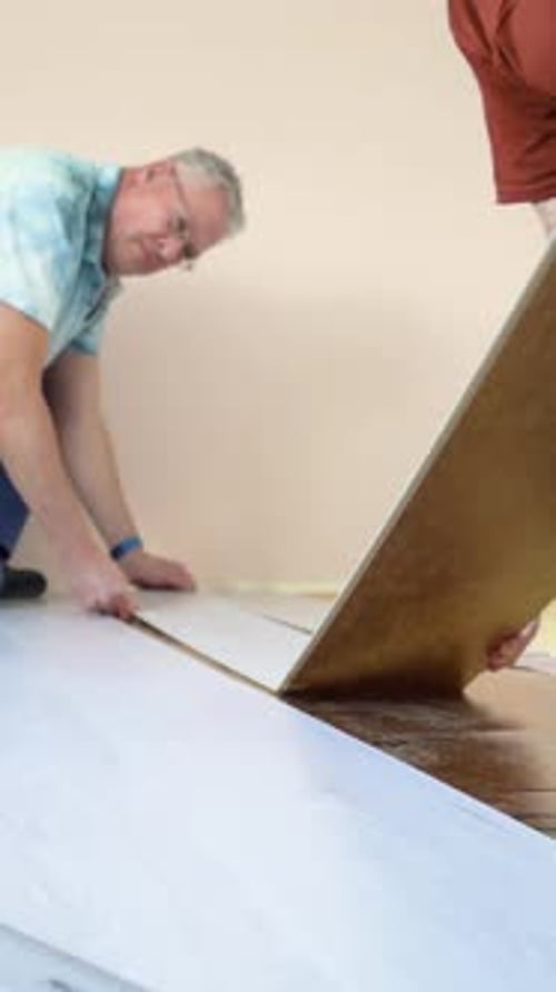 Adults Installing New Flooring Indoors