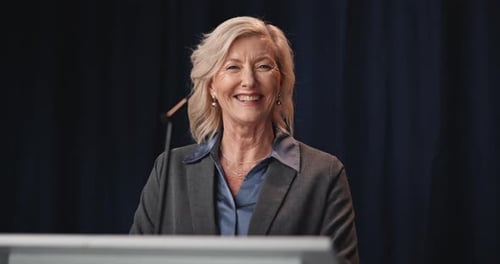 Smiling Woman in Blazer at Podium