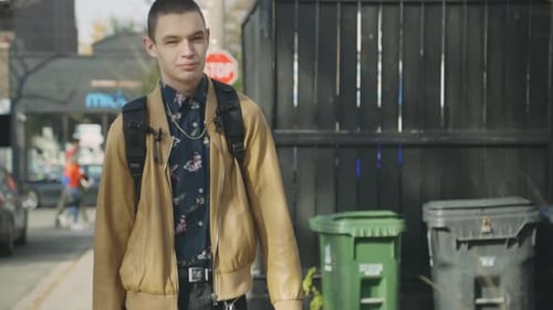 A Casual Young Man In Brown Coat And Backpack Walking Down The Urban Street - Slow Motion