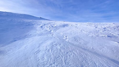 View of the mountain on a very windy sunny day. Wind swirling the snow in the air. Outdoor winter.