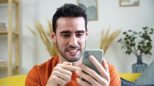 Man Smiling and Using Smartphone at Home