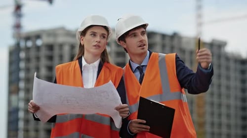 Zwei Ingenieure untersuchen Baupläne und besprechen das Projekt auf der Baustelle aus nächster Nähe