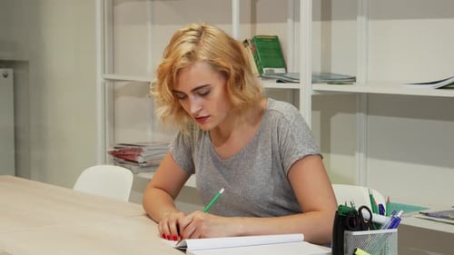 Thoughtful Young Woman Jotting Down Notes While Studying