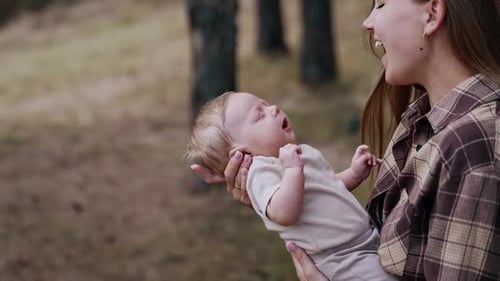 Loving mom puts her baby close to her chest. Caucasian woman with her child outdoors in autumn.
