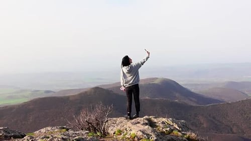 Woman Taking Pictures on Mountain Peak