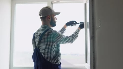 Man in Uniform Does Pvc Window Installation with a Screwdriver