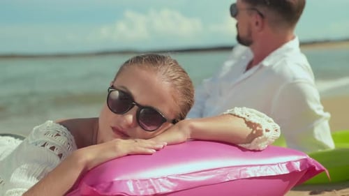 Couple Relaxing on Inflatable Raft at Beach