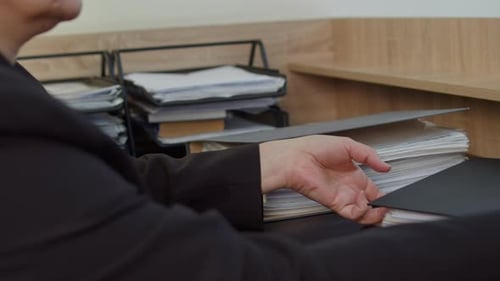 Close Up of Hands Placing Binder on Document Stack