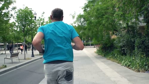 Young man jogging on city sidewalk in super slow motion at 240fps