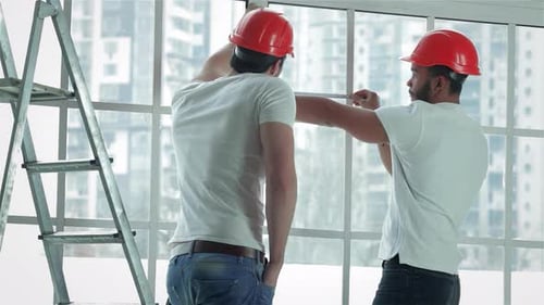 Zwei Arbeiter messen fleißig Fenster für Reparaturen
