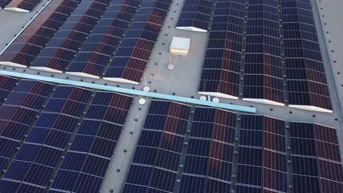 Rows of solar panels providing sustainable energy on a commercial building roof, drone shot