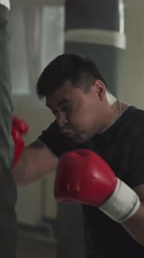 Fighter Punches Stuffed Bag with Hooks in Gym