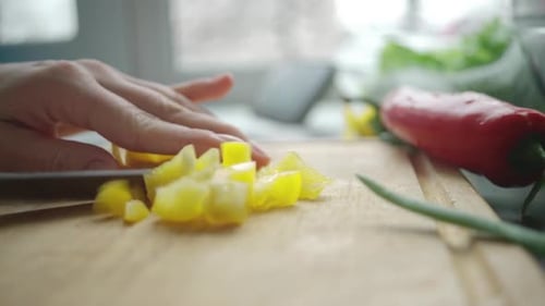 Hand Chopping Yellow Bell Pepper on Cutting Board