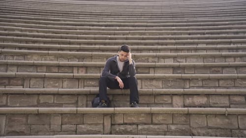 Man with Dark Hair Sits on Stone Steps