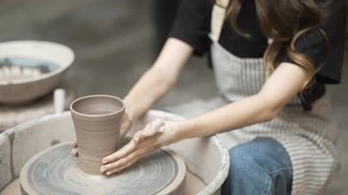 Young women is making earthenware at workshop.