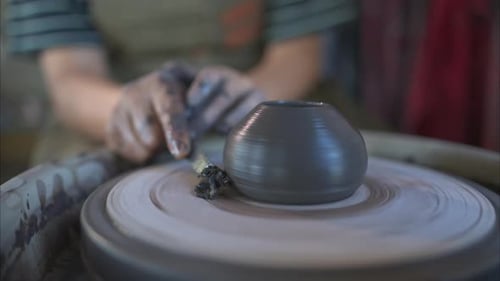 Mains d'un potier, créant un bocal en terre sur le tour de poterie