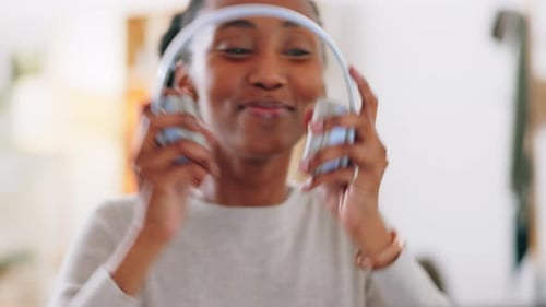 Woman Putting on Headphones and Using Computer at Home
