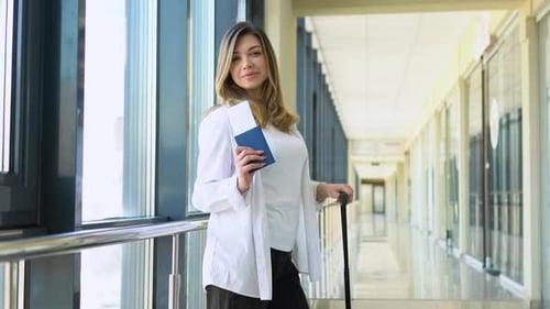 Woman Holding Passport and Boarding Passes Ticket in Airport Hallway Waiting for Document Control