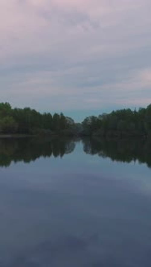 Low Angle Flying Over the Lake Clouds and Trees Reflection in Water Vertical Video