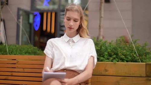 Woman Writing in Notebook on Bench in City
