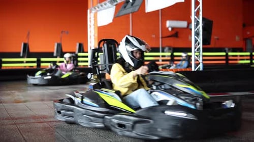 Focused Teenager Driving a Go-Kart on an Indoor Track