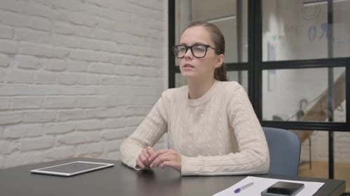 Woman Sitting Attentively at Desk in Office