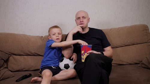 Father and Son Watching TV with Soccer Ball