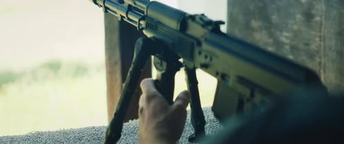 Person Adjusting Rifle on Bipod at Outdoor Range