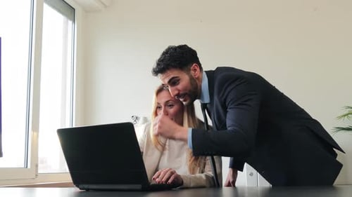 Successful Business Partners Celebrating Victory While Working on a Laptop in a Bright Office Space