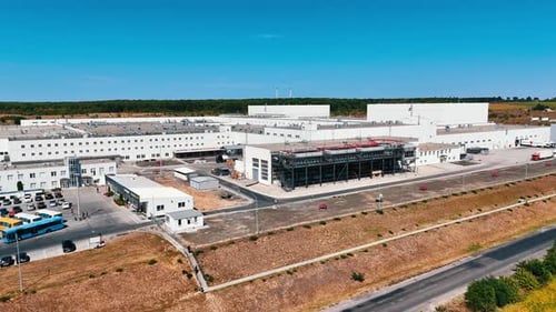 S'envoler d'une usine avec une grande zone de stationnement devant elle.