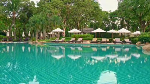 Umbrella and chair around swimming pool in hotel resort - holiday and vacation concept