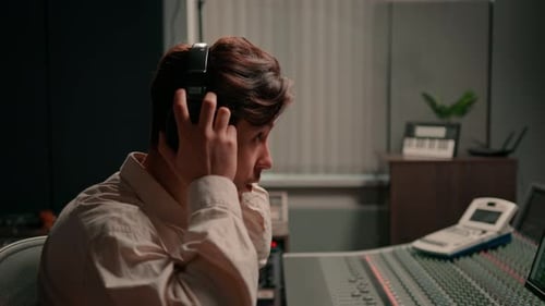 Energetic audio engineer producer working in recording studio mixing tracks on console and hit maker