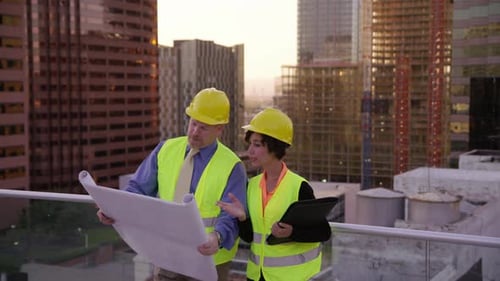 Two Construction Supervisors Look at Plans on Rooftop Architect