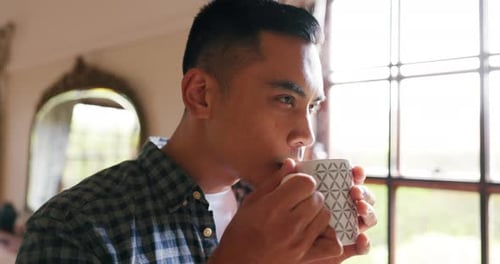 Man Drinking Hot Beverage by a Bright Window