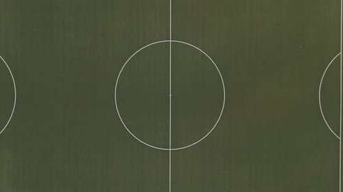 Top Down View of an empty, green football field in the middle of the forest, Drone Footage