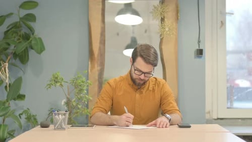 Young Businessman Writing Documents in Office
