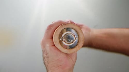 Hands Grinding Spices in Wooden Grinder