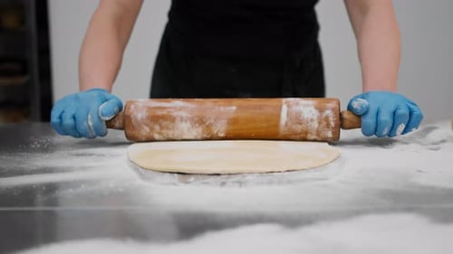 The kitchen in the bakery - the process of preparing cinnabons, the woman baker forms doughs