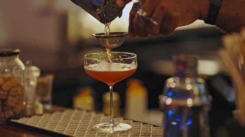 Bartender Pouring Cocktail Through Strainer into Glass