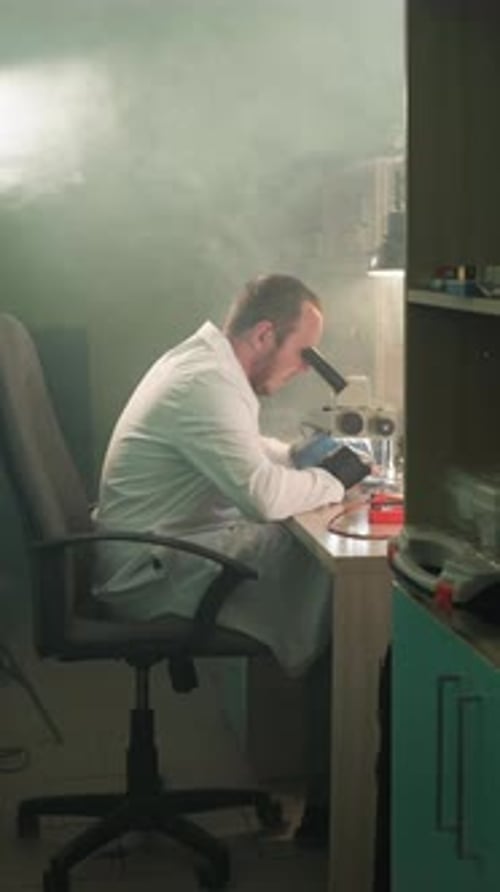 Scientist Using a Microscope in Dark Laboratory